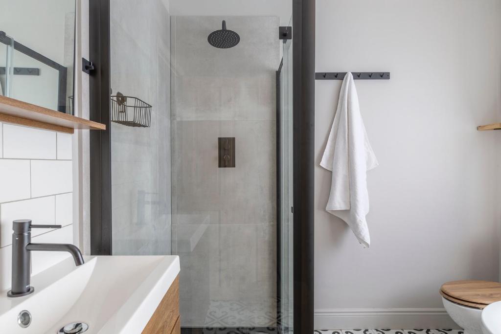 a bathroom with a shower and a white sink at Palm Bay Beach House in Margate