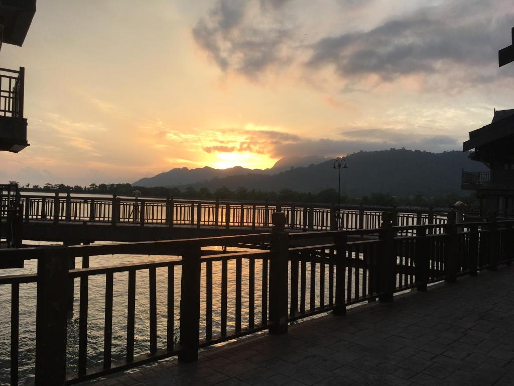 a bridge over the water with the sunset in the background at THE LAGOON WATER CHALET in Kampung Padang Masirat