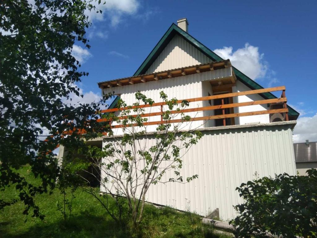 un edificio bianco con un tetto verde su una collina di Family farm Jezera a Žabljak