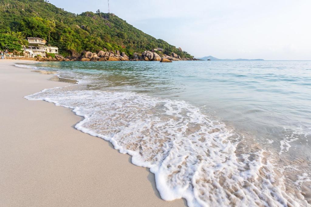 einen Strand mit Meer und Felsen im Hintergrund in der Unterkunft Penthouse Crystal Bay Apartments in Ban Lamai