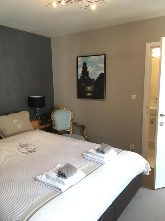 a bedroom with a large white bed with a chair at Begijnhofstudio's in Tongeren