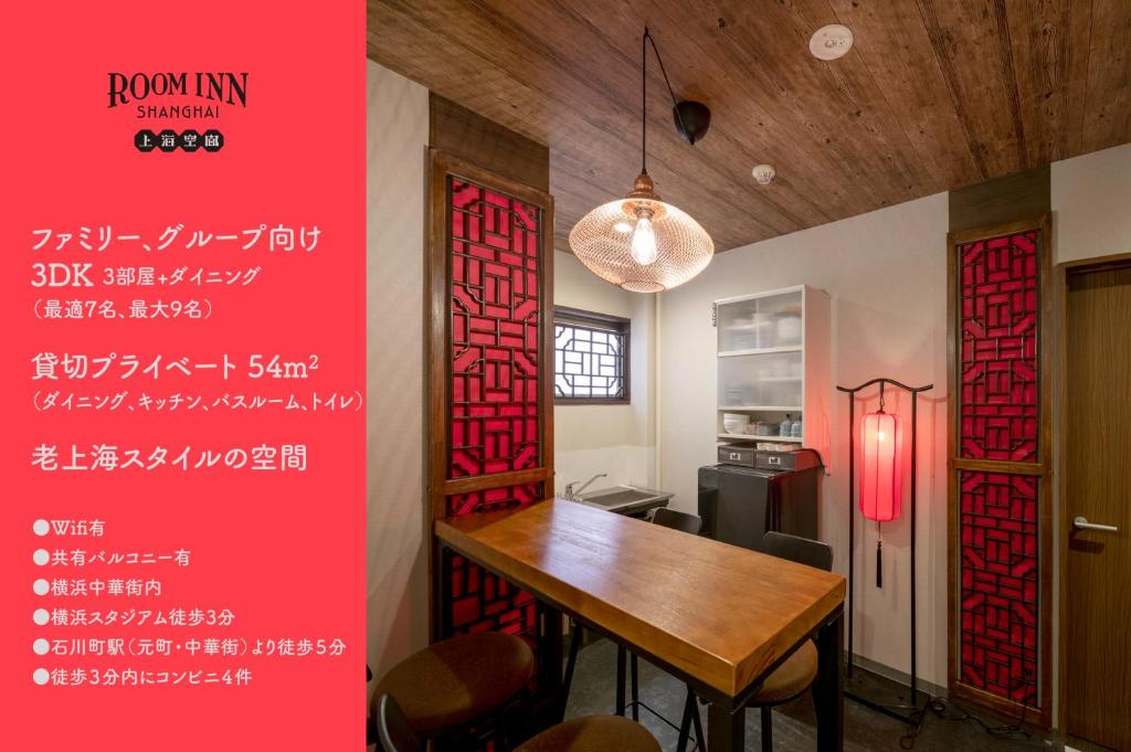 une salle à manger avec une table et un mur rouge dans l'établissement Room Inn Shanghai 横浜中華街 Room1-ABC, à Yokohama