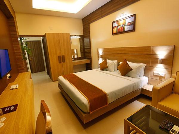a bedroom with a bed and a couch and a television at Imperial Heights in Deoghar