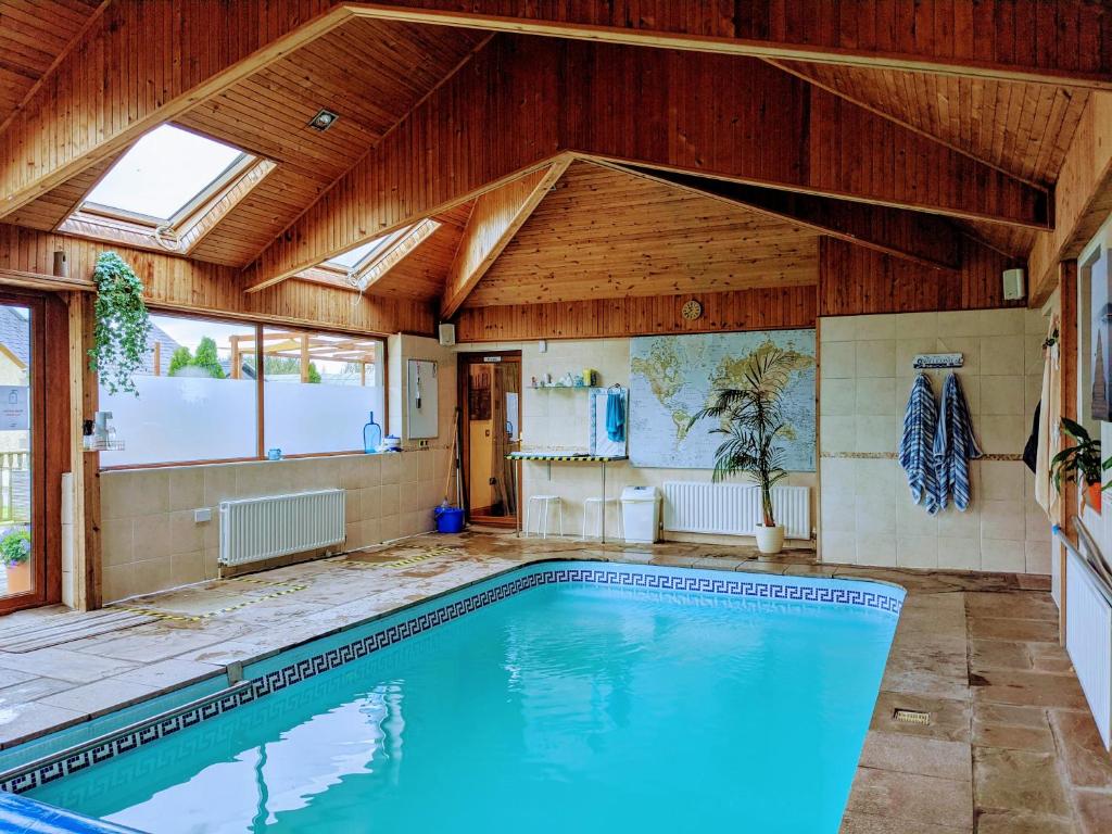 a swimming pool in a house with a wooden ceiling at Glynvohr House in Carryduff