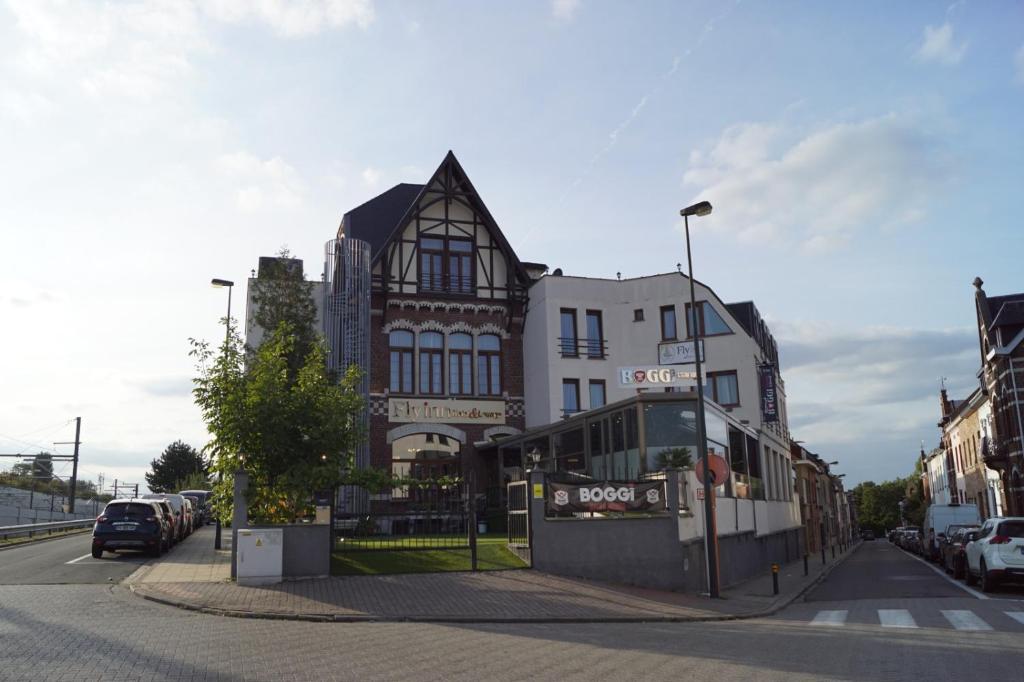 a large building on a city street with cars parked at Fly inn Hotel Lounge in Machelen