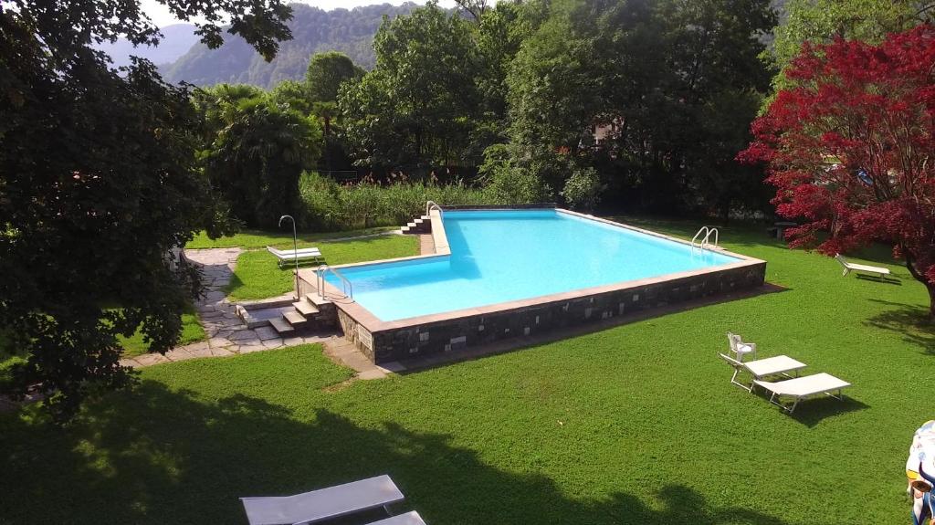 einen Pool auf einem Rasenplatz mit zwei Liegestühlen in der Unterkunft Hotel Fonte dei Fiori in Caslano