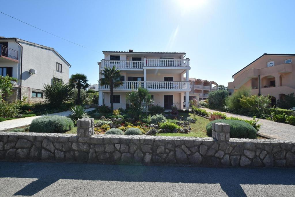 ein großes Haus mit einer Steinmauer vor einem Garten in der Unterkunft Apartments Marinela in Njivice