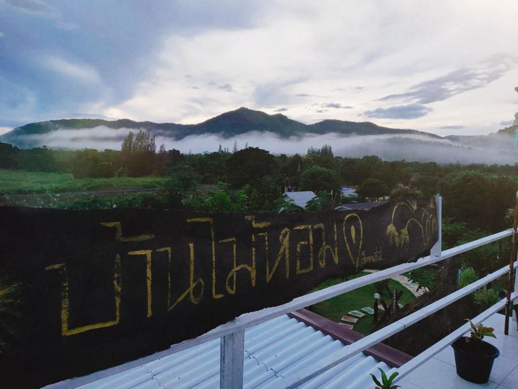 a sign for a hotel with a view of the mountains at Baan Mai Hom Resort Suan Phueng in Suan Phung