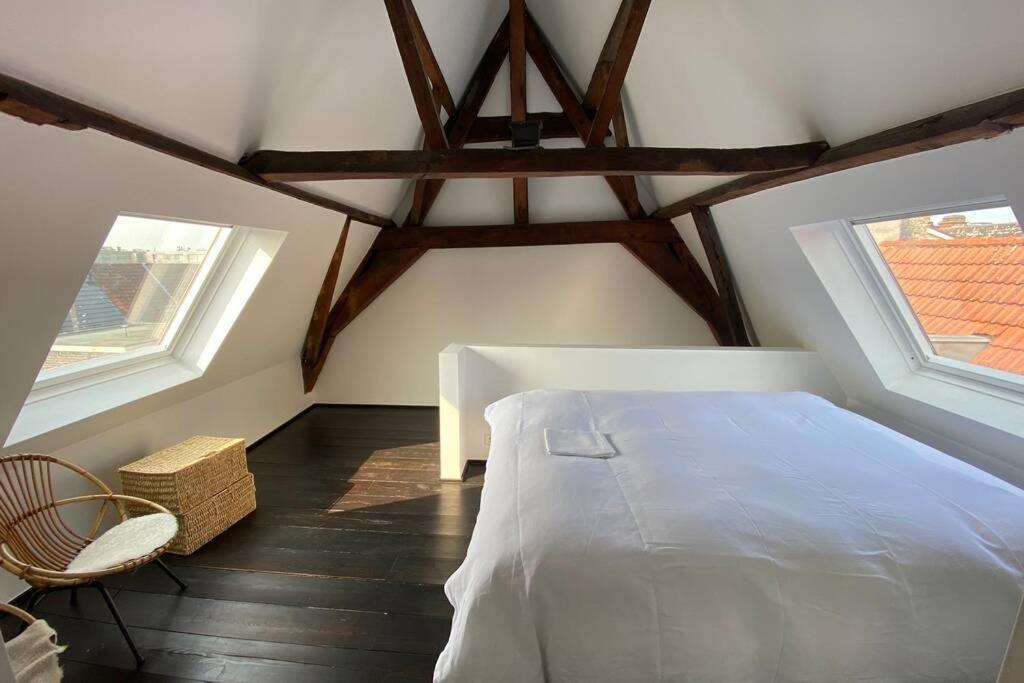 a bedroom with a white bed and two windows at GLORIA LOFT GENT in Ghent