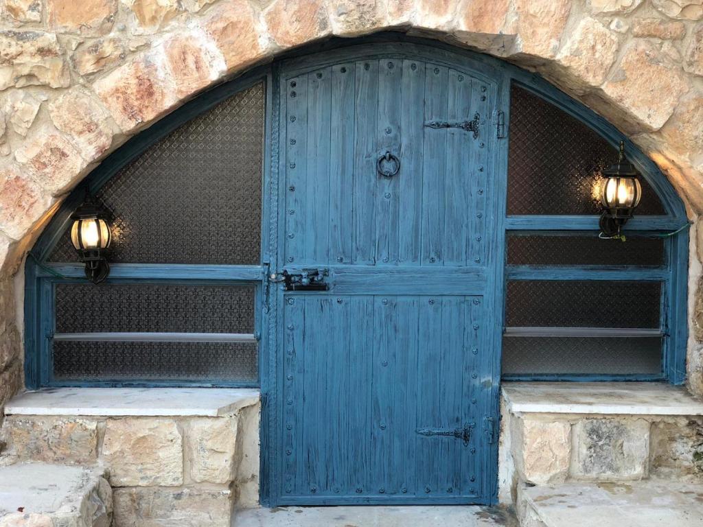 una puerta azul en un edificio de piedra con dos luces en CUENTO DEL AMOR en Mi‘ilyā