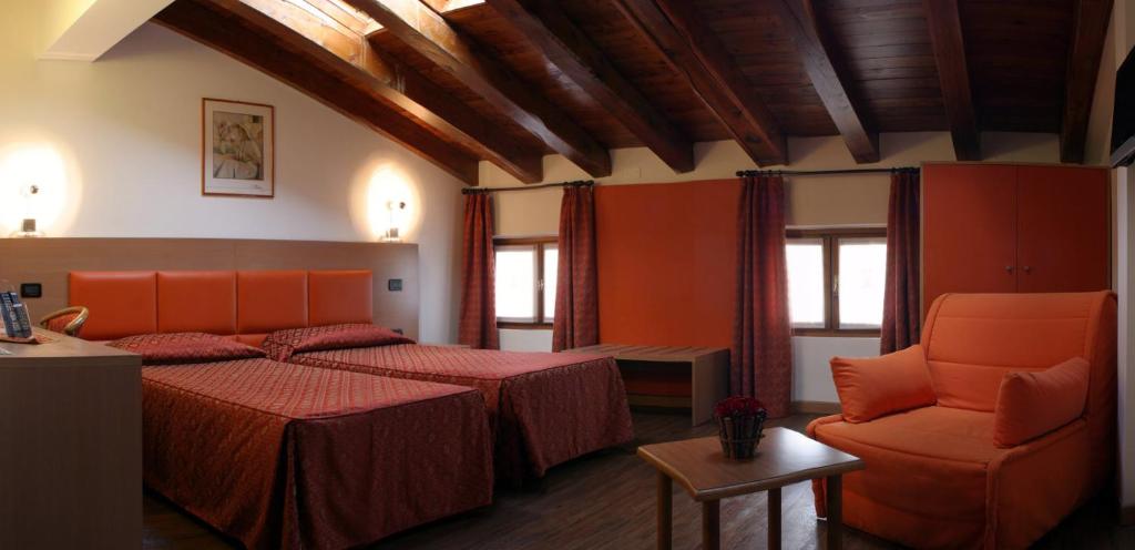 una habitación de hotel con 2 camas y una silla en Hotel and Wellness Patriarca, en San Vito al Tagliamento