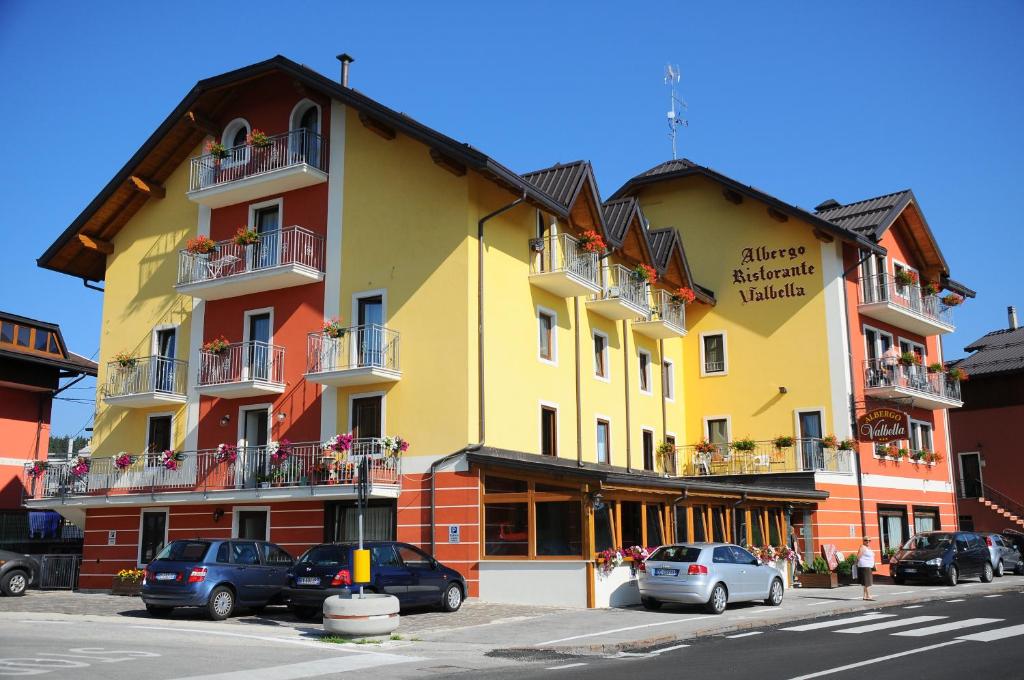 un edificio giallo con macchine parcheggiate di fronte di Albergo Valbella a Gallio