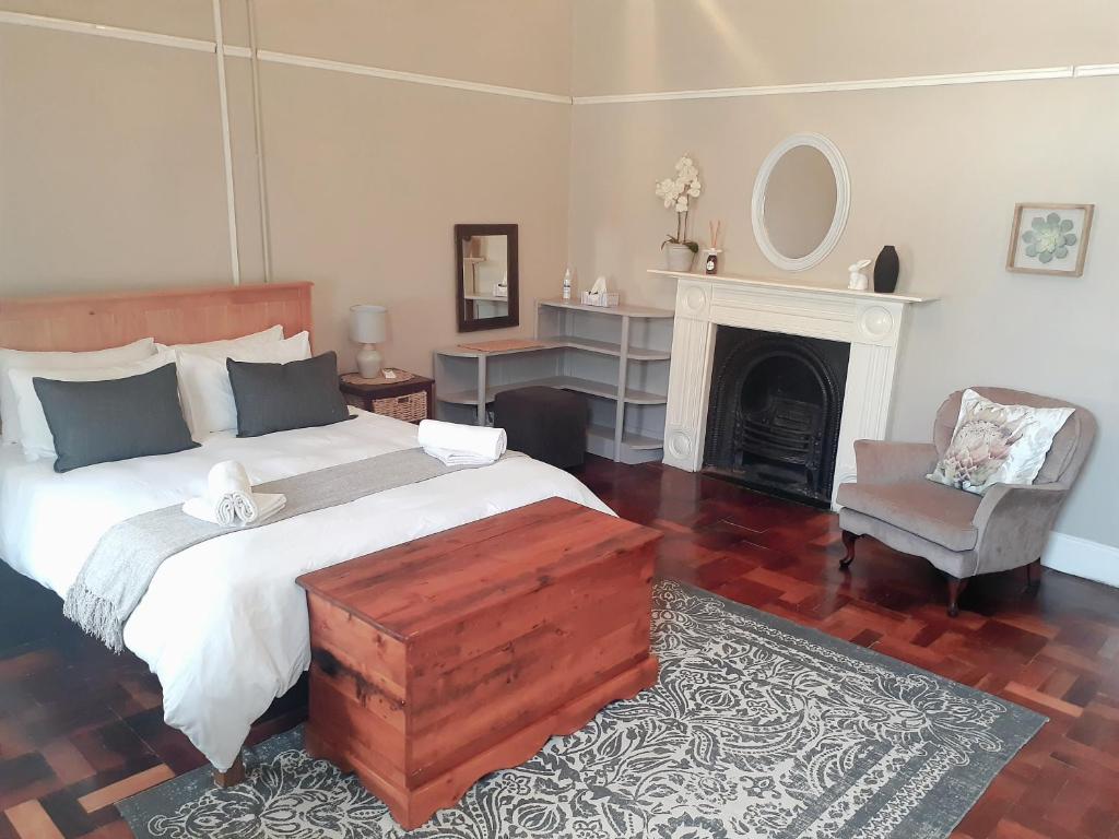 a bedroom with a bed and a chair and a fireplace at Boer & Brit in Graaff-Reinet