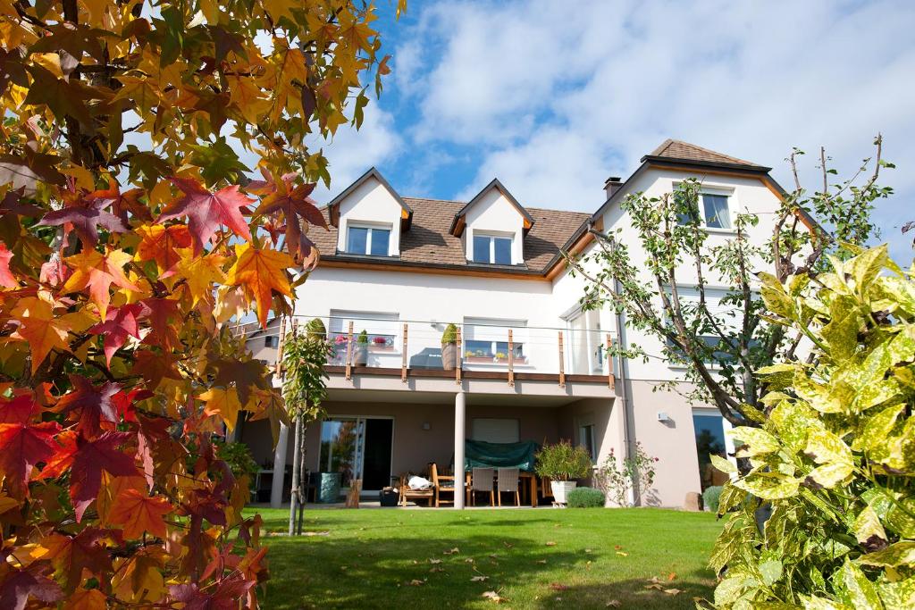 una gran casa blanca con un patio con hojas de otoño en La Pénate des 3 Châteaux en Husseren-les-Châteaux