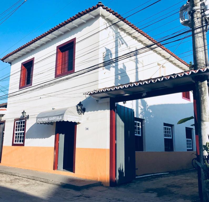 a white building with colorful doors on a street at Pousada Gabriela in Paraty