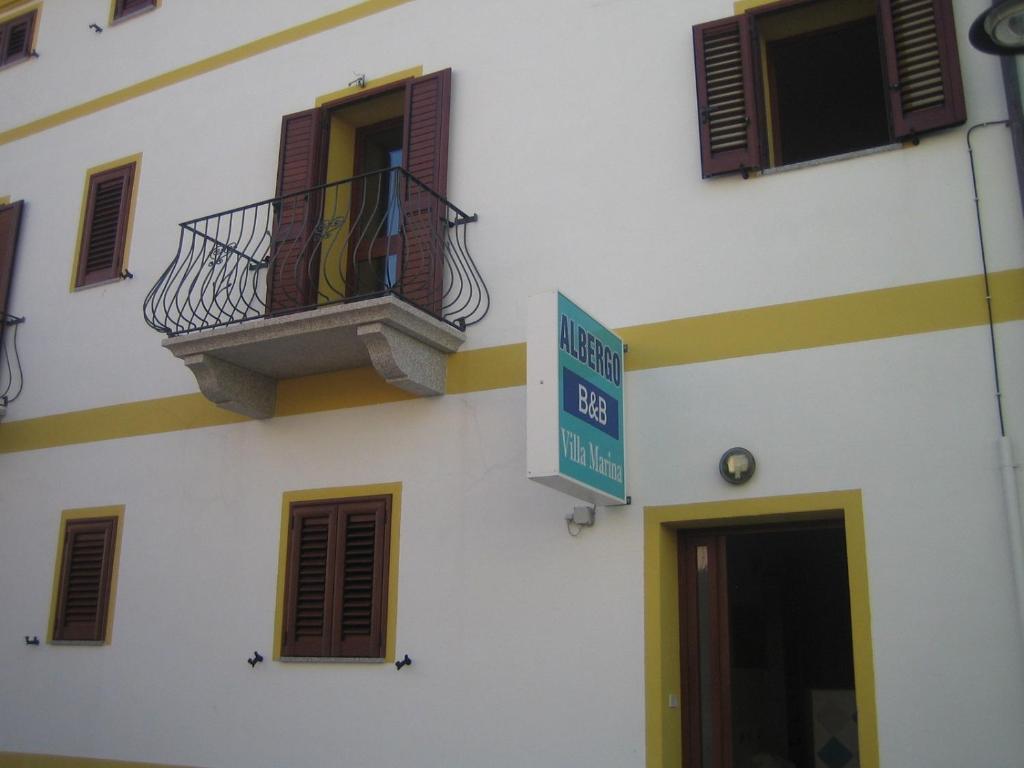 un edificio con balcón y una señal en él en Albergo Villamarina, en Santa Teresa Gallura
