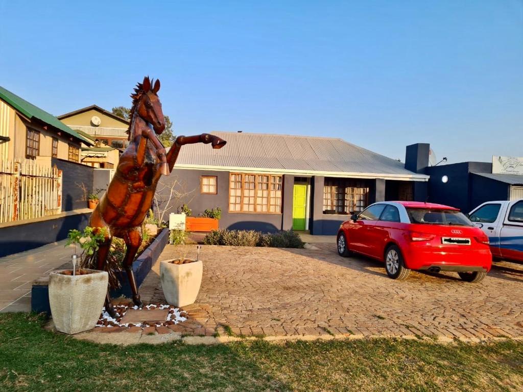 un coche aparcado frente a una casa con una estatua en Green Venus, en Kaapsehoop