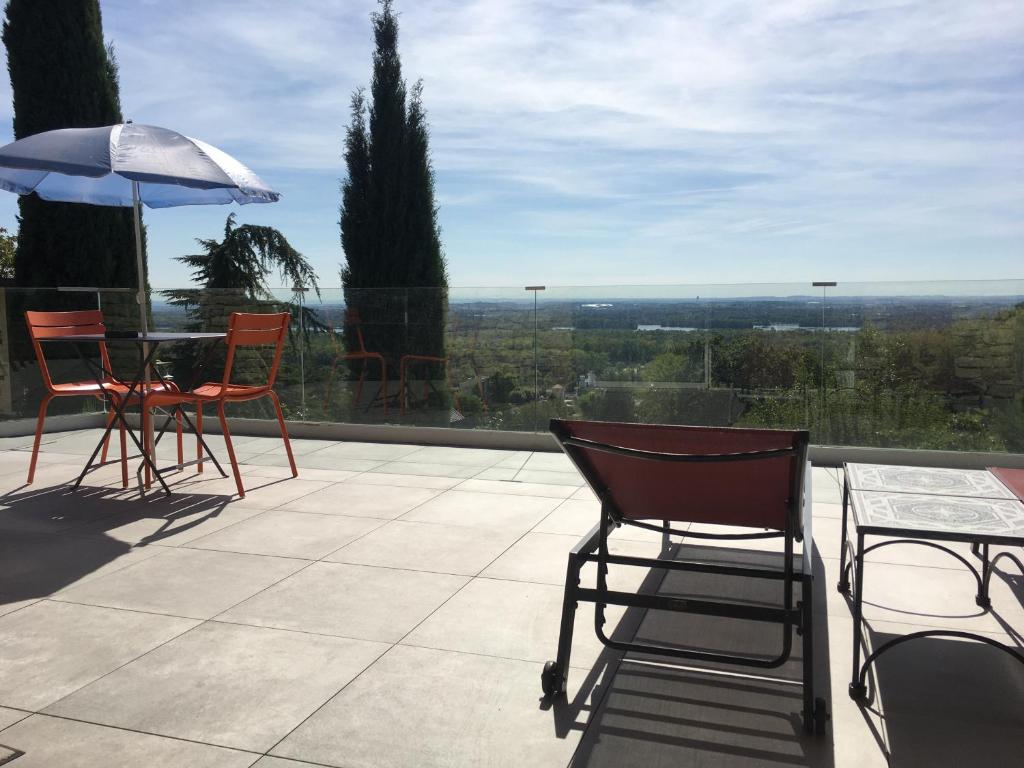 eine Terrasse mit Stühlen, einem Tisch und einem Sonnenschirm in der Unterkunft La Villa du Rhône in Miribel