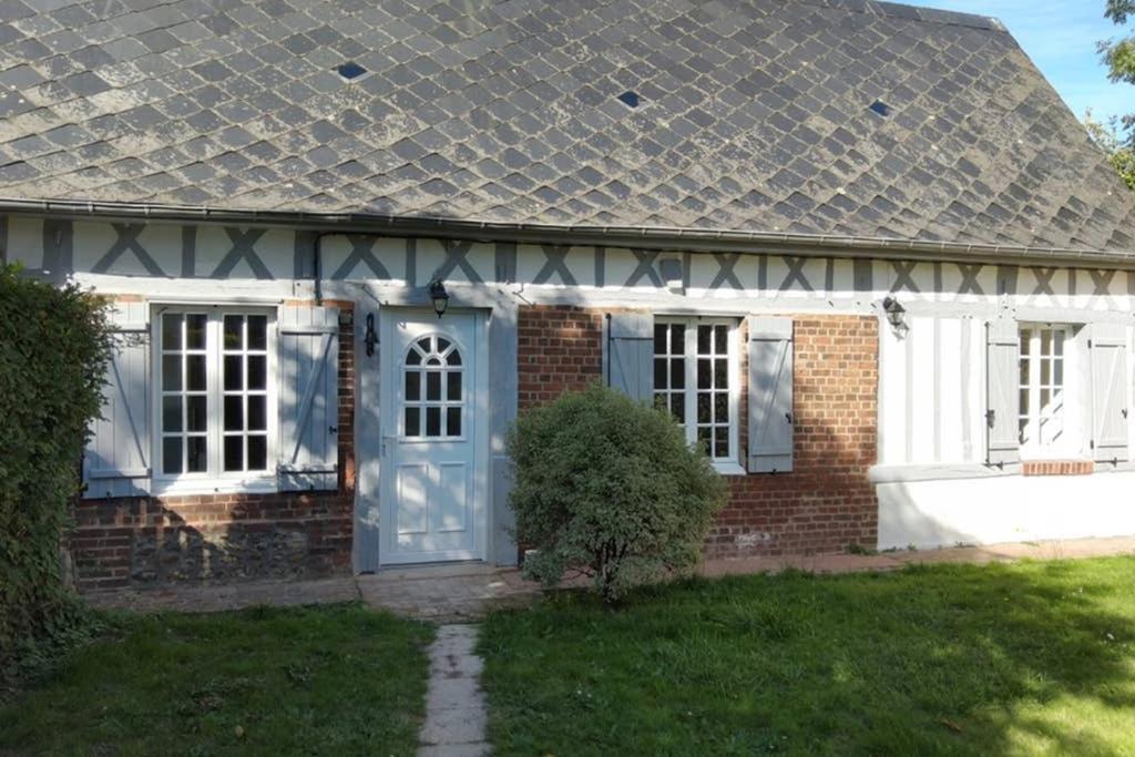 uma casa de tijolos com uma porta azul e um quintal em charmante maison normande luneray em Luneray