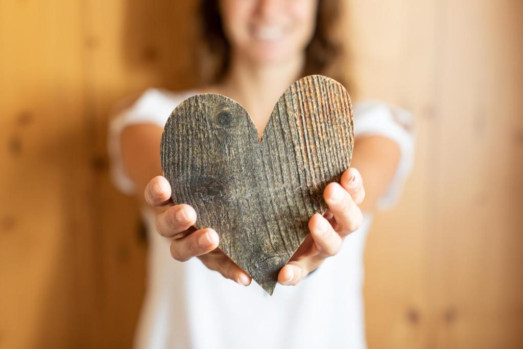 une femme tenant un cœur en bois entre ses mains dans l'établissement Meisser Romantica "adults only", à Guarda