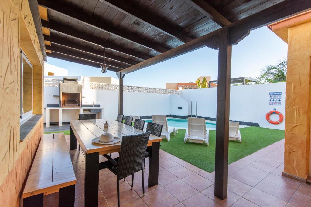 een patio met een houten tafel en stoelen bij Villa Annalisa in Corralejo