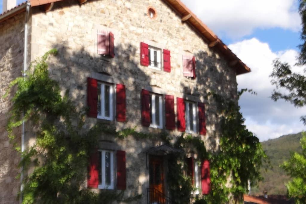 Un vieux bâtiment avec des volets rouges dans l'établissement GITE L'EPICURIEN, à Sainte-Agathe