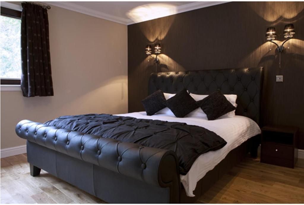 a bedroom with a large bed with a leather headboard at Ben Arthur's Bothy Luxury Flat in Arrochar