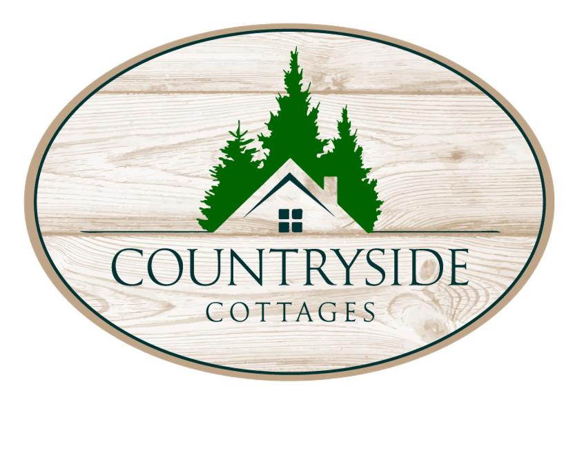 una señal para un camping con una casa y árboles en Countryside Cottages en Bartonsville