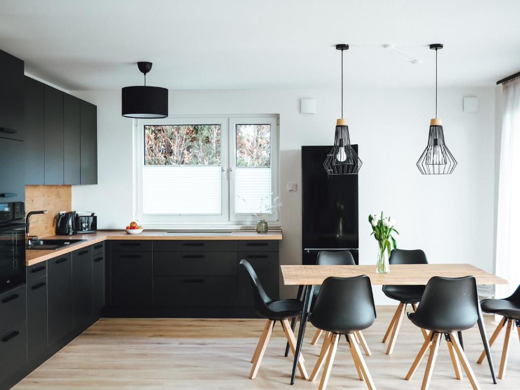 a kitchen with black cabinets and a wooden table at Seeblick & Terrasse! Moderne Ferienwohnung 96qm in Großräschen