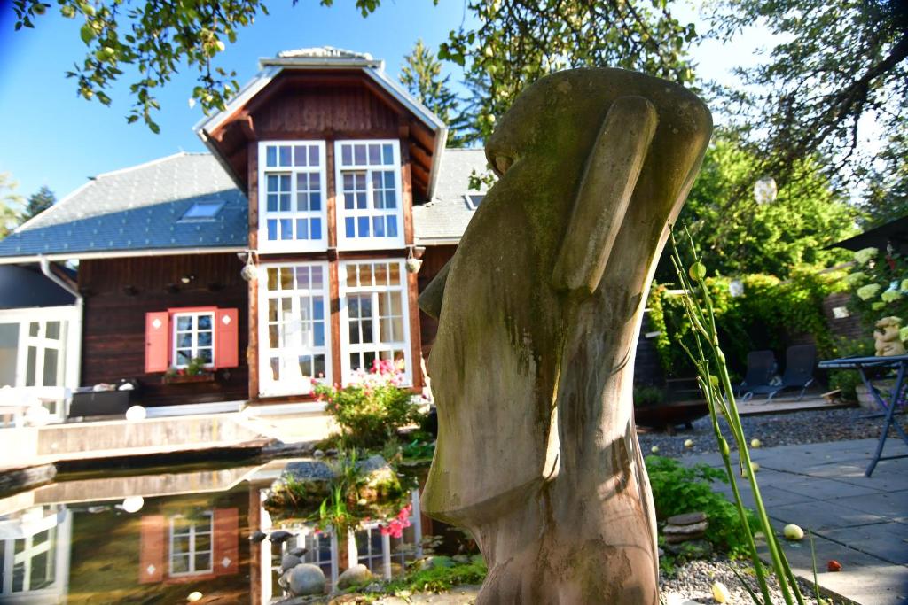 una estatua de madera frente a una casa en Naturforsthaus Gartenblick für tier- und naturverbundene Menschen, en Preitenegg