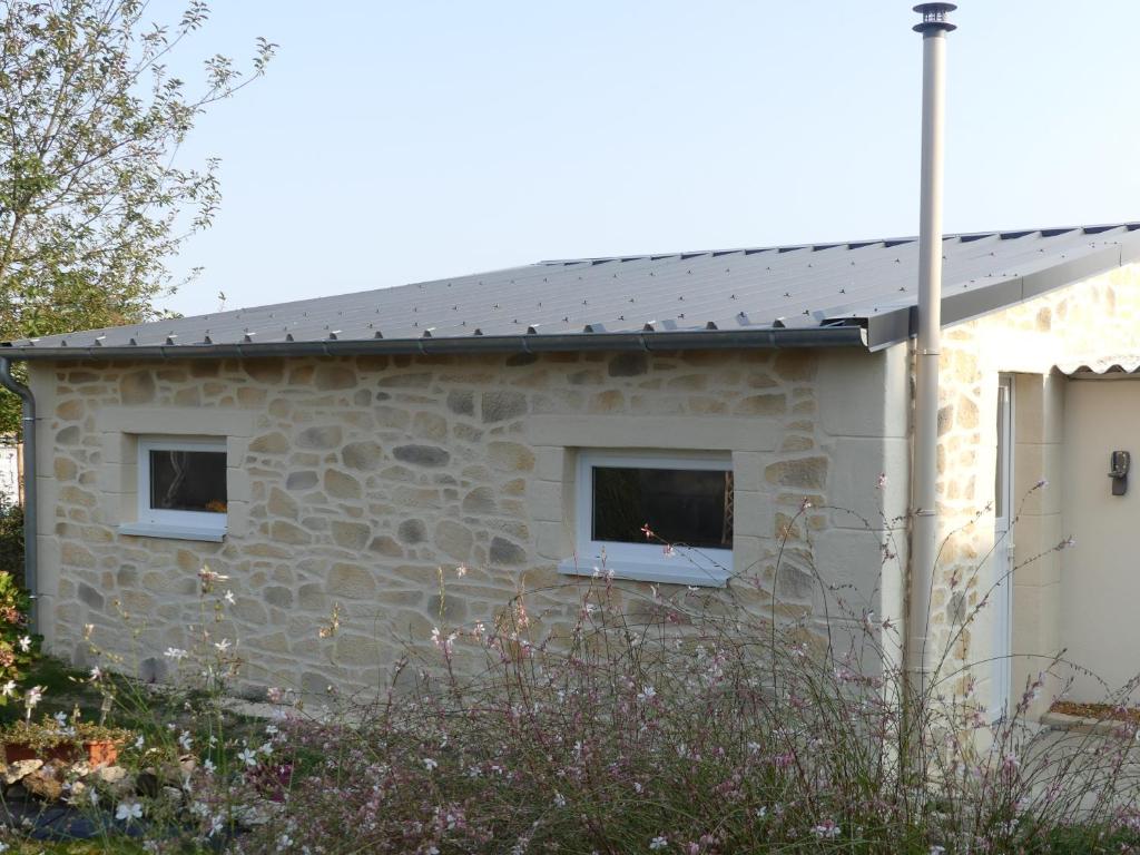 une maison en pierre avec deux fenêtres et un toit dans l'établissement charmant studio 35m² au calme proche du circuit, à Saint-Gervais en-Belin