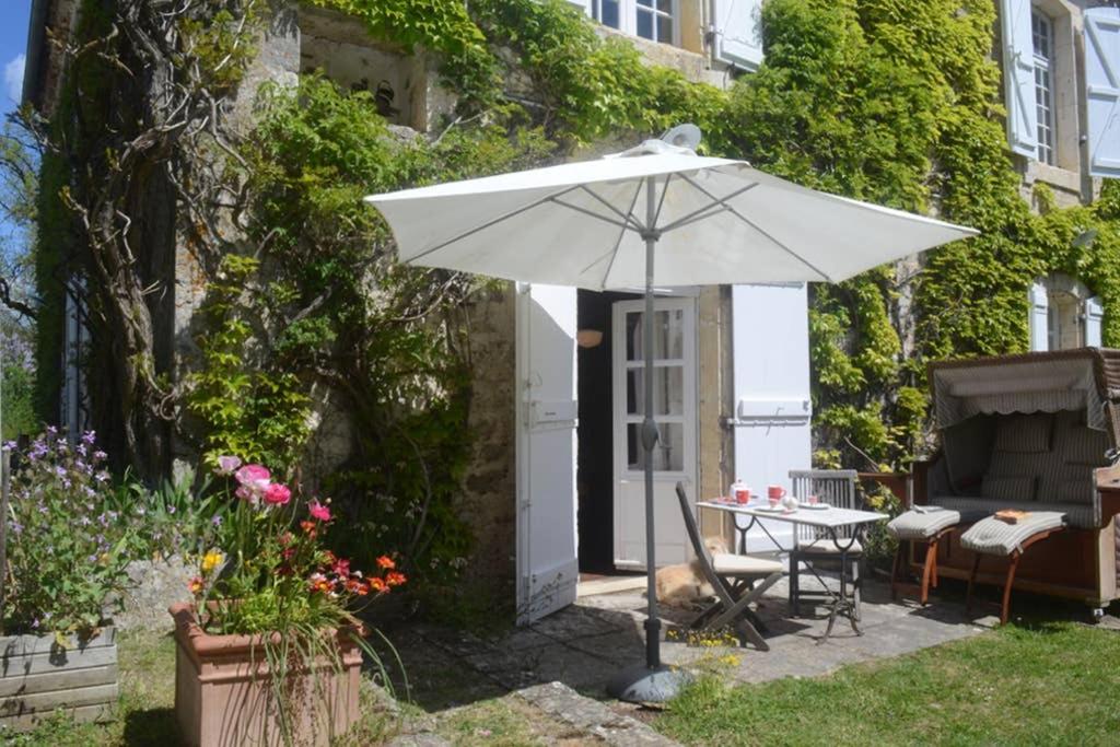 un patio con sombrilla, mesa y sillas en l'Empereur - La Maïsou, en Sérignac