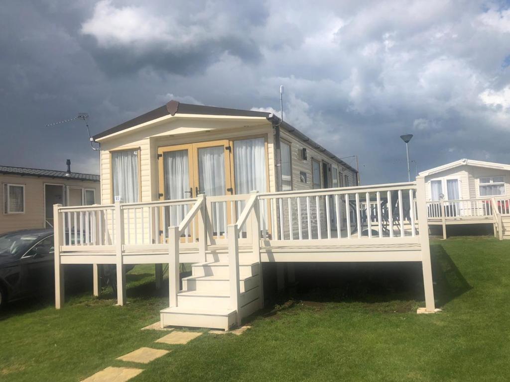 a house with a large white deck on the grass at Vista Caravan Hire in Seasalter