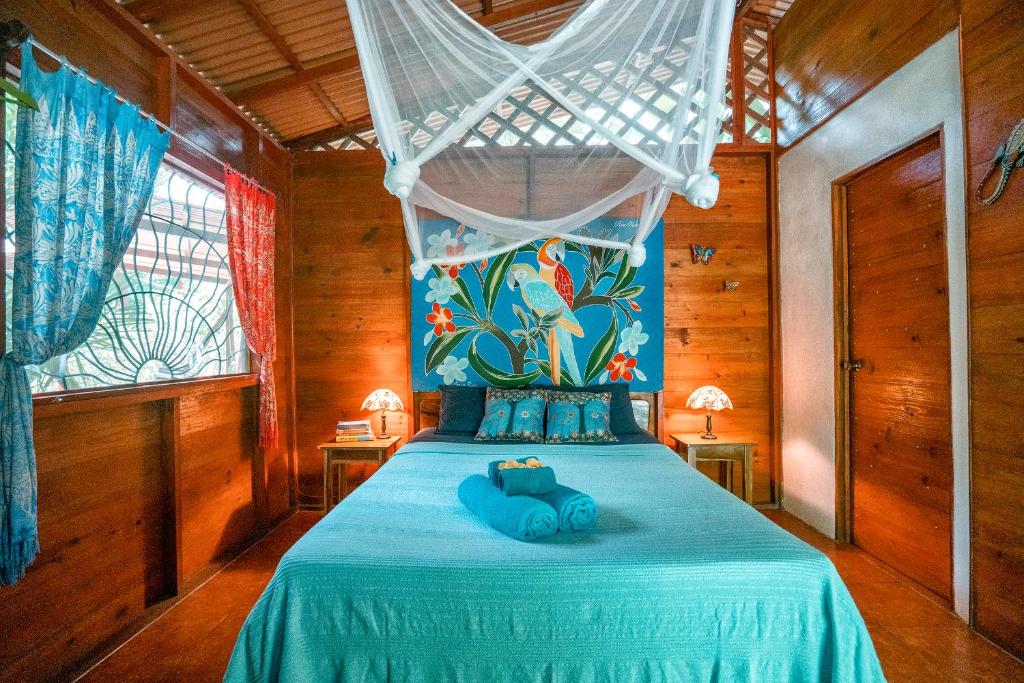 a bedroom with a blue bed with a canopy at Casitas Las Flores in Puerto Viejo