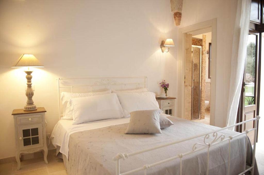 a bedroom with a white bed and a lamp at Donna Lucrezia in Pezze di Greco