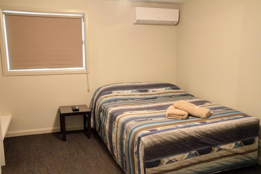 a bedroom with a bed with two towels on it at Ivanhoe Hotel Motel in Ivanhoe