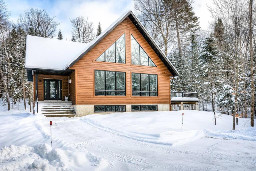 una casa in legno nella neve con la neve di 3BDRM Zen Tremblant Chalet - Ski/Hike/Swim a Lac-Superieur