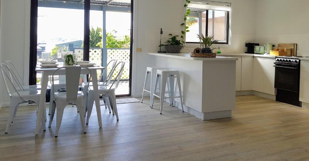 a kitchen with a table and chairs in a kitchen at HelloSailor HolidayRental FirePit NBN AppleTV KingBed in Clayton Bay