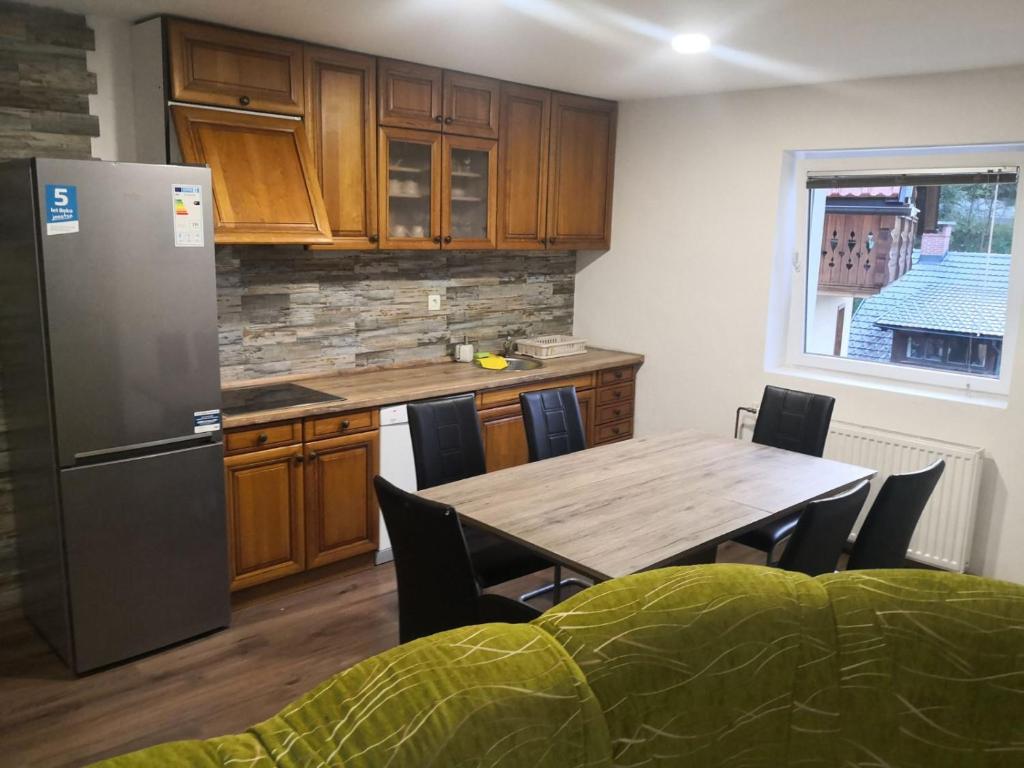 a kitchen with a table with chairs and a refrigerator at Apartma Alja in Kranjska Gora
