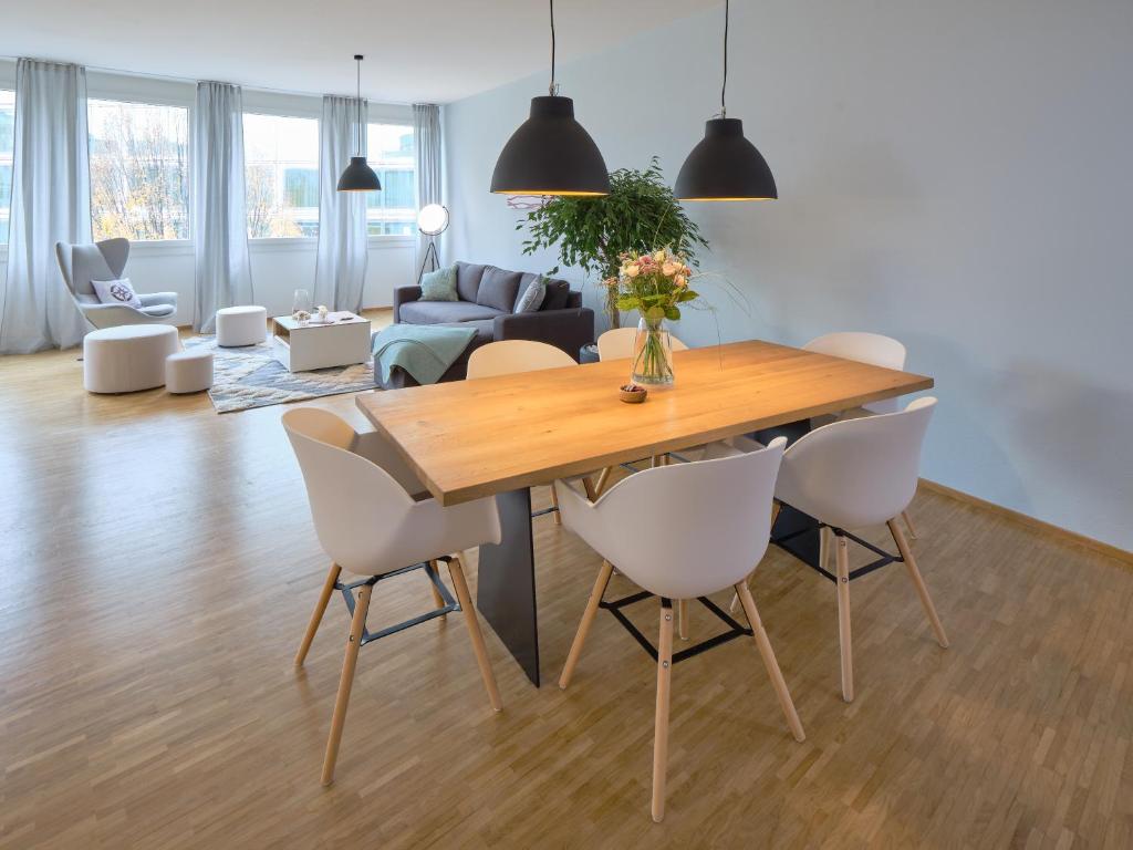 a dining room and living room with a wooden table and chairs at OfficeWerft Business-Apartments in Luzern