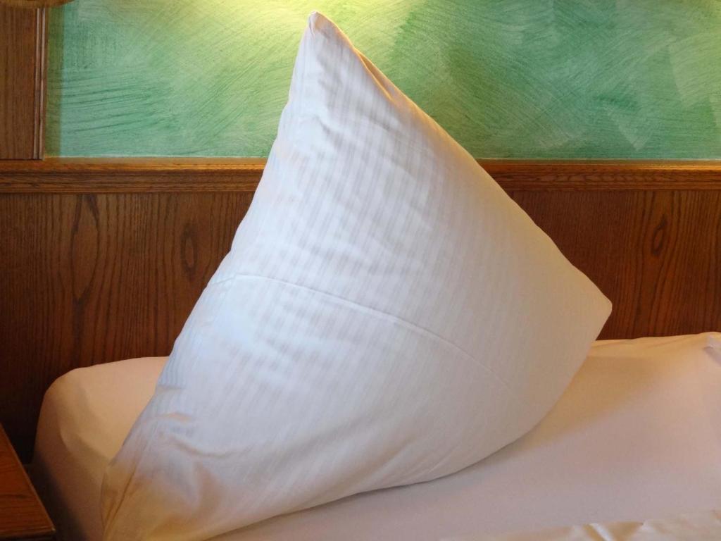 a white pillow sitting on top of a bed at Beim Haxenwirt in Immenstadt im Allgäu