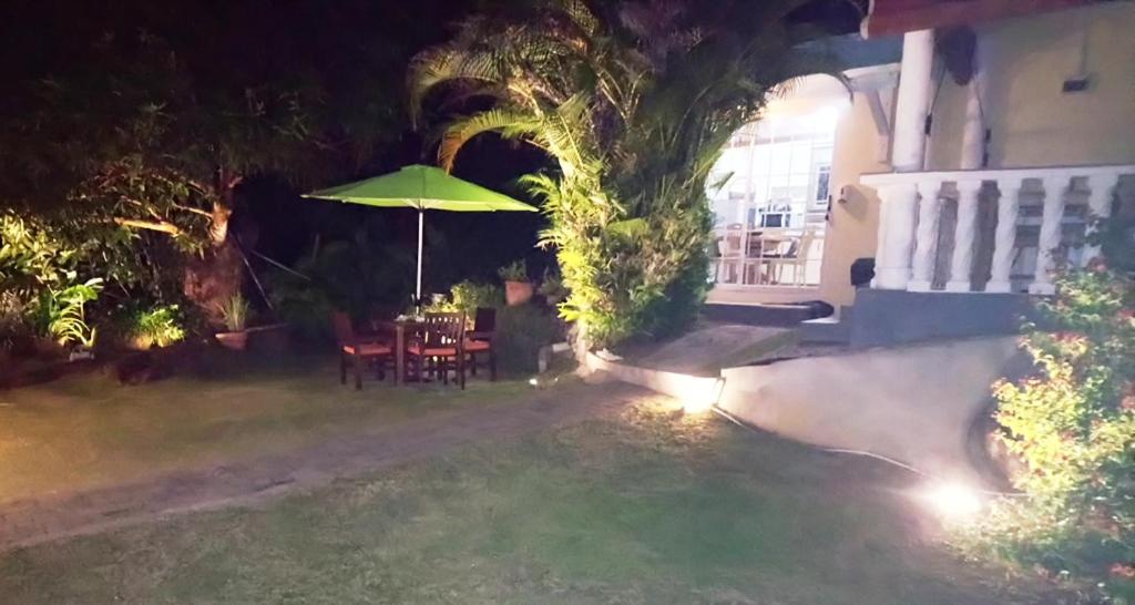 a patio with a table and an umbrella at night at The Reef Palm in Anse aux Pins
