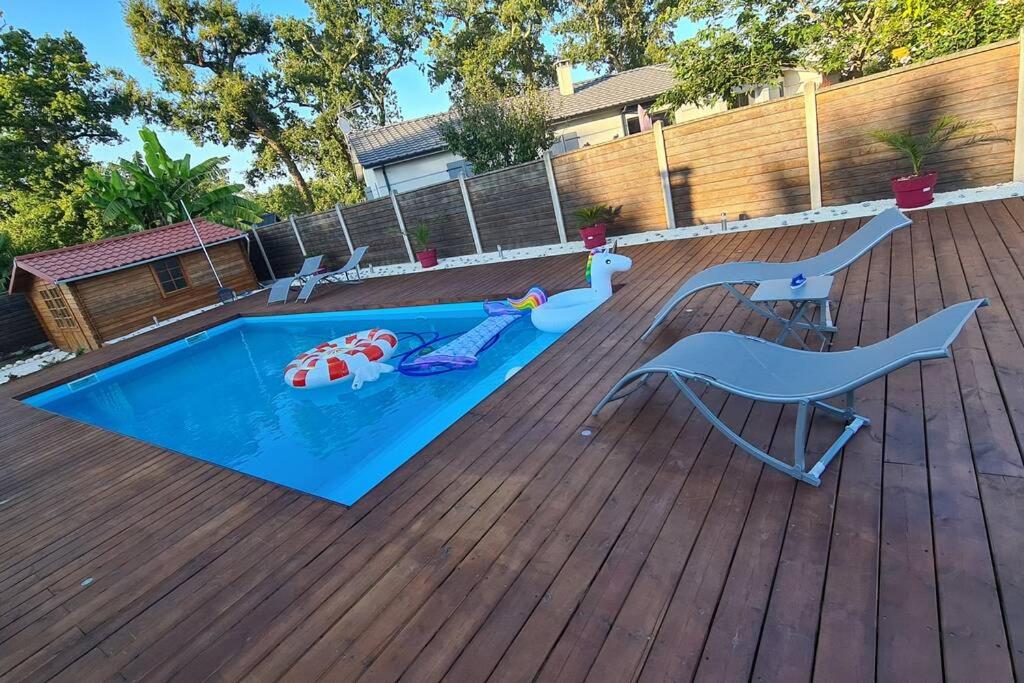 um quintal com uma piscina e um deque de madeira em Agréable Maison entre Bordeaux et le Bassin em Saint-Jean-dʼIllac