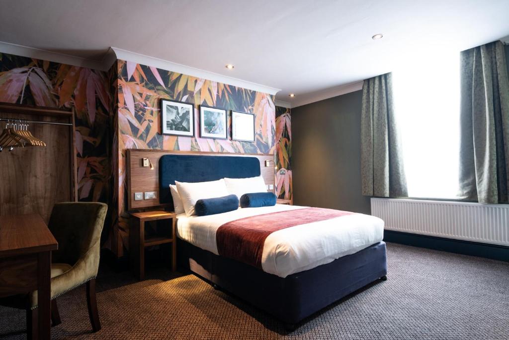 a hotel room with a bed and a desk and a chair at The Merlin by Innkeeper's Collection in Alderley Edge