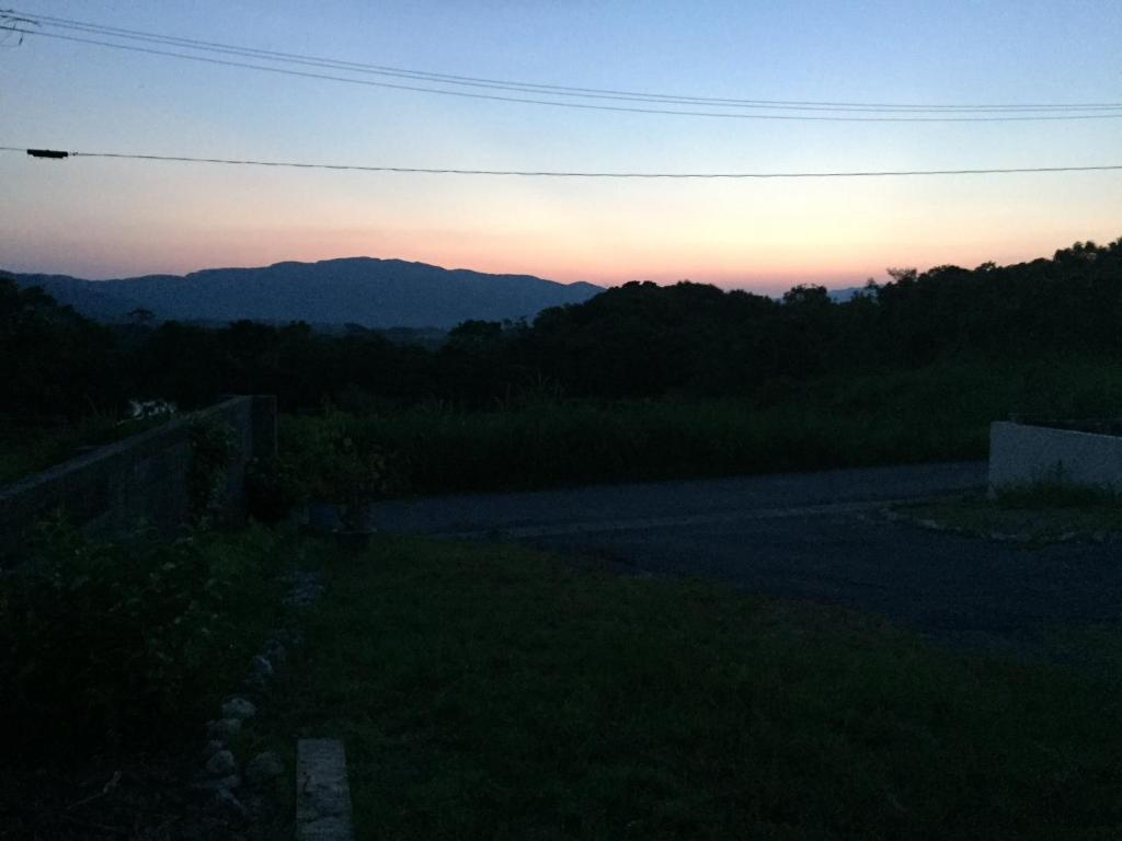 a sunset over a road with mountains in the background at Shimaotoya in Iriomote