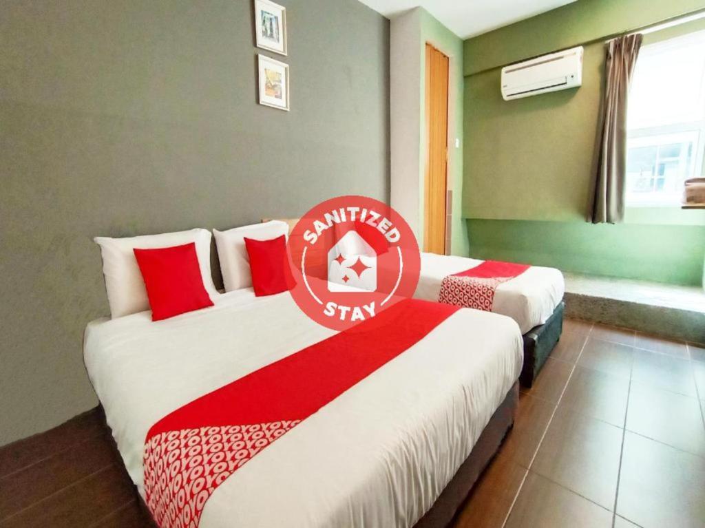 a hotel room with two beds with red and white sheets at Super OYO 89465 Golden Lounge in Kuching
