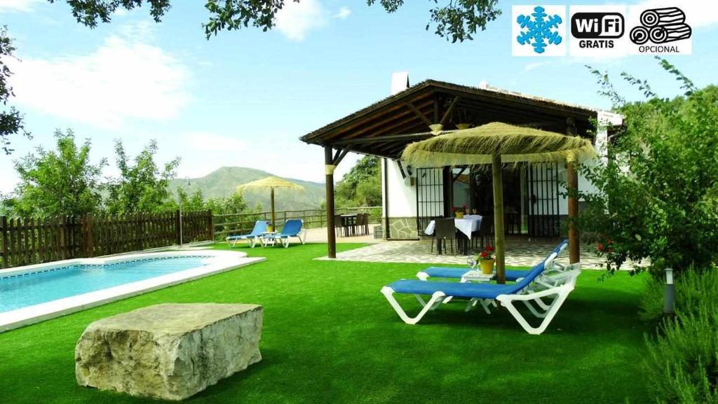 um quintal com uma piscina, uma cadeira e um guarda-sol em Casa Rural El Chaparro em El Chorro