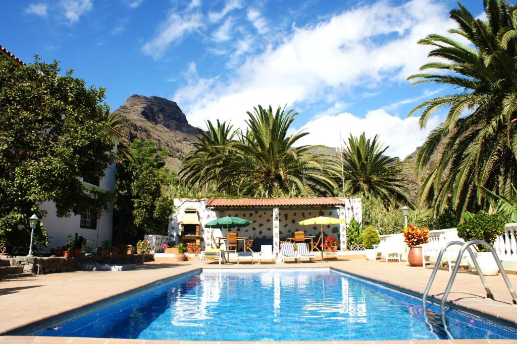 a swimming pool with a resort with a mountain in the background at Apartamentos Nelly in Valle Gran Rey