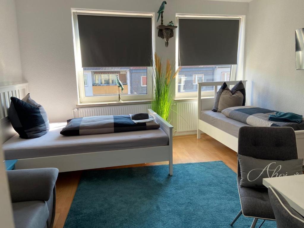 a bedroom with two beds and a chair and two windows at City Studio 2 in Bremerhaven