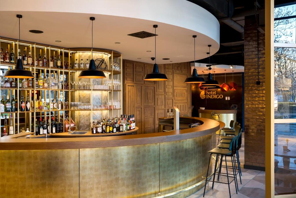 a bar with a wooden counter and some lights at Hotel Indigo Dresden - Wettiner Platz by IHG in Dresden